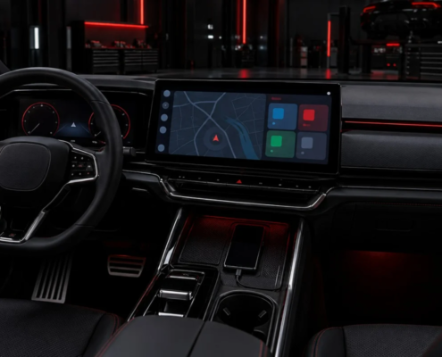 Cockpit eines modernen Autos mit großem Infotainment-Bildschirm und angeschlossenem Smartphone in einer dunklen Werkstatt mit roter Beleuchtung